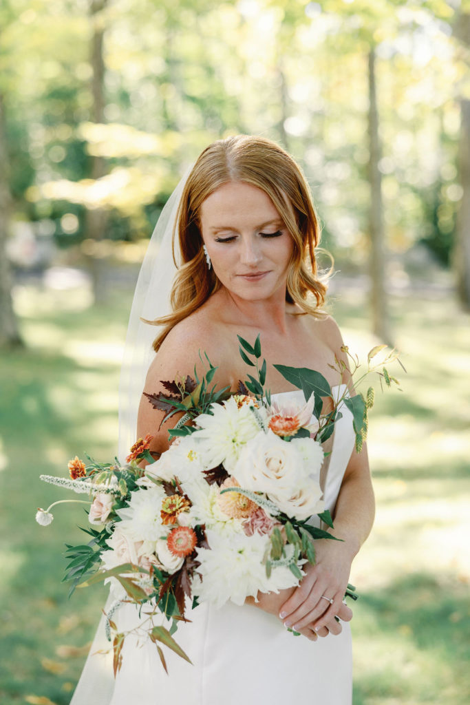 bride wearing a veil and holding a large bouquet of autumn flowers