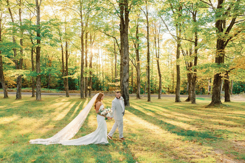 bride and groom walking through a maple grove during the fall