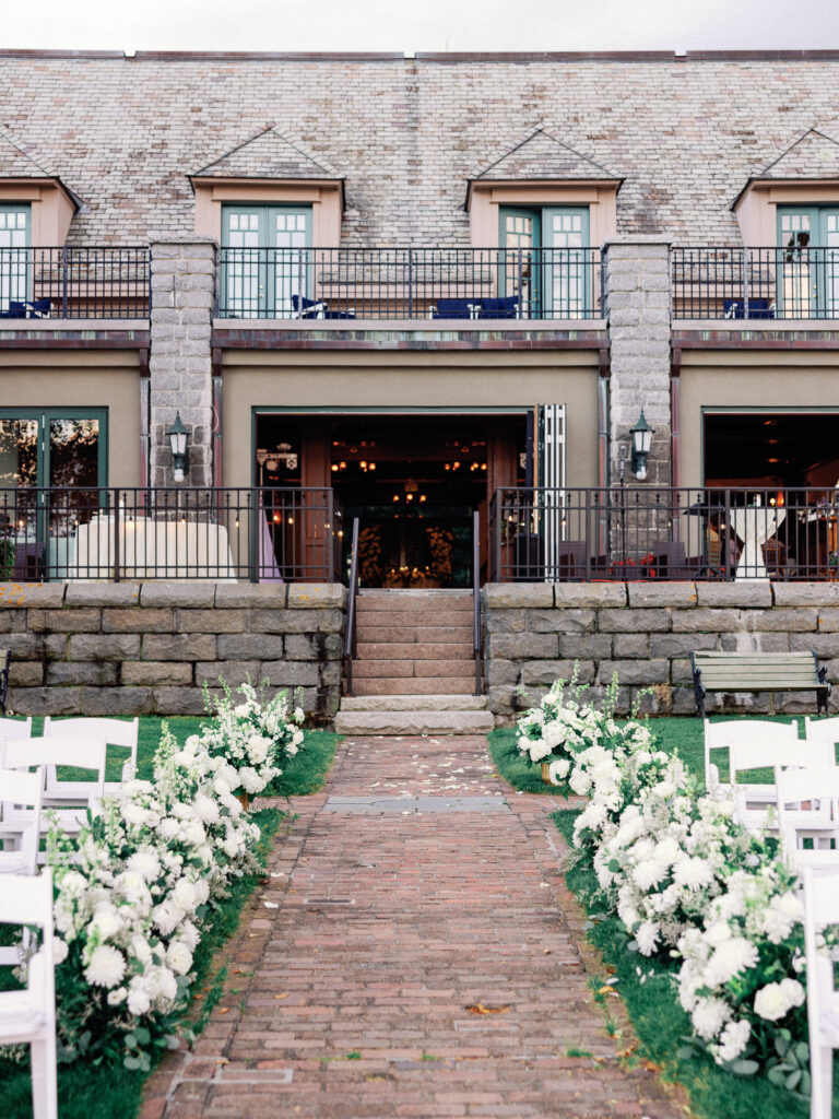 Entrance to the Stone House at the Bar Harbor Regency lined with white flowers on a wedding day in Maine.