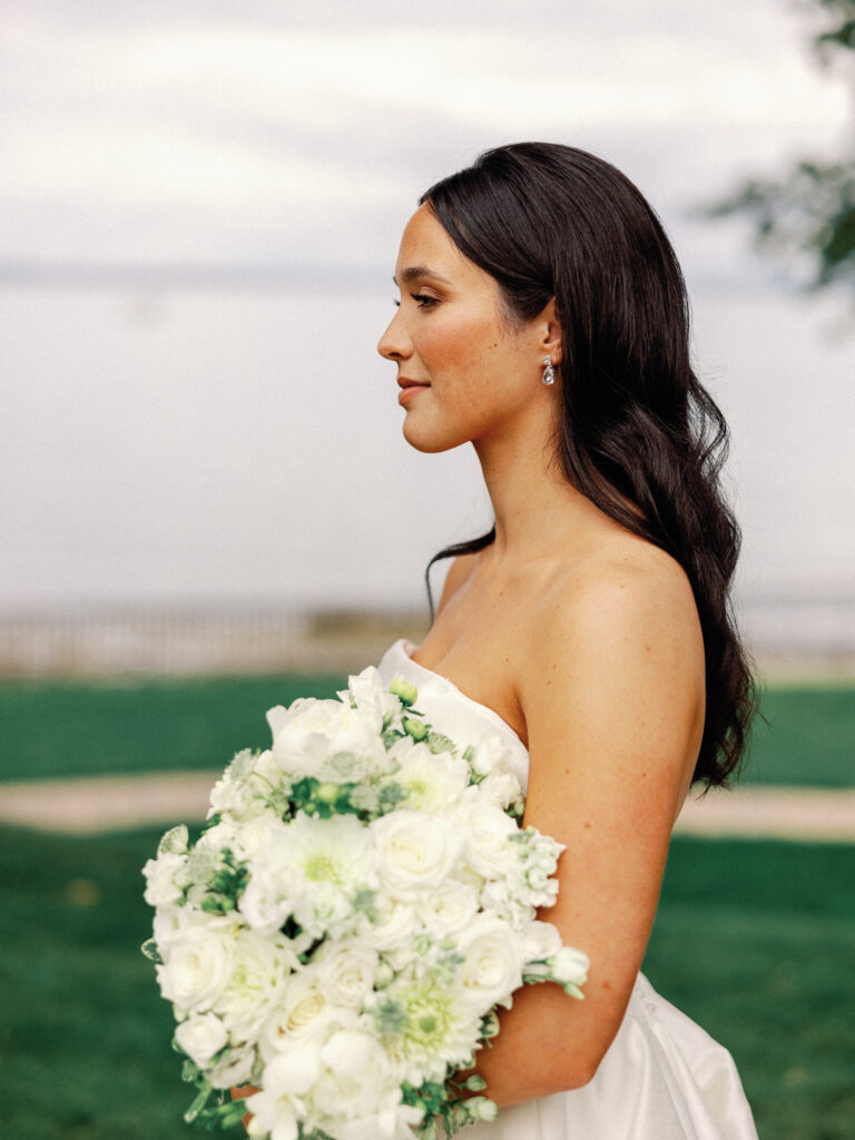 Classic bridal portrait of a side profile of a bride while she is holding her bouquet of white flowers on her wedding.