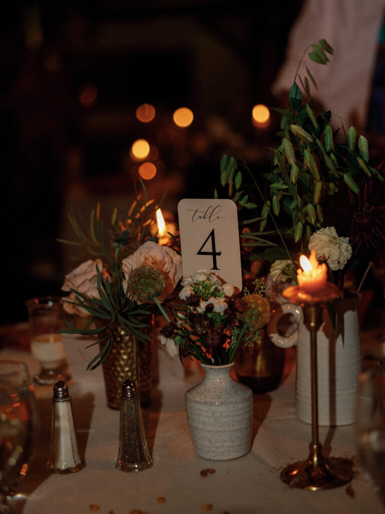 Simple reception ideas for table decor. Small bud vases and votive candles lined the tables with tall tapers winding between them for a cozy and simple reception decor look.