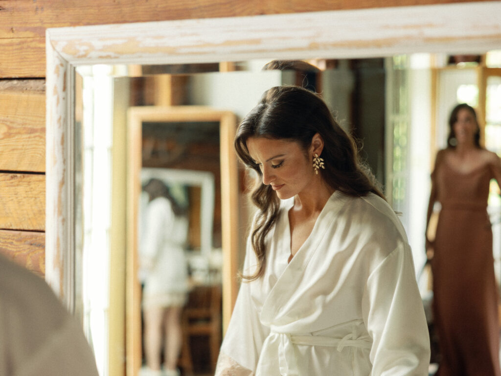 Bride's reflection bounces through multiple mirrors while she gets ready at the River House at Riverside Farm in Pittsfield, Vermont.