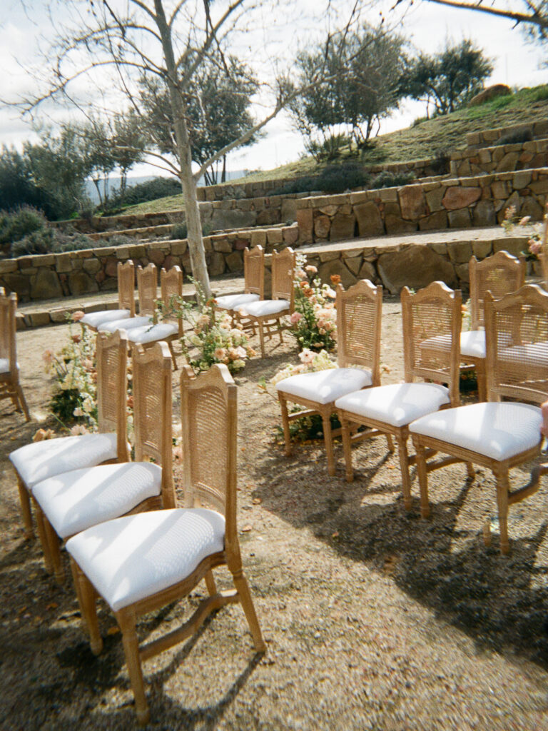 White and tan chairs at a lux wedding reception cast shadows from the sun.