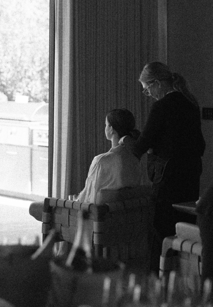 Bride getting ready while sitting in a chair for hair and make up on her wedding day.
