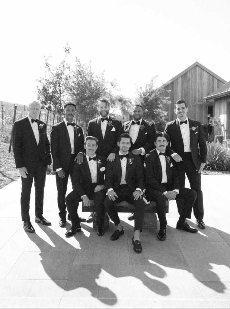 Black and white editorial shot of groomsmen sitting together during a wedding at Stanley Ranch.
