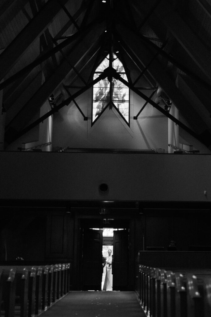 Silhouette of wedding ceremony inside a dark chapel.