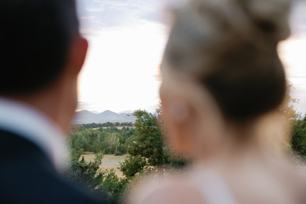 Bride and groom look at the Rocky Mountains in the distance of their Colorado wedding reception at Shift Workspaces