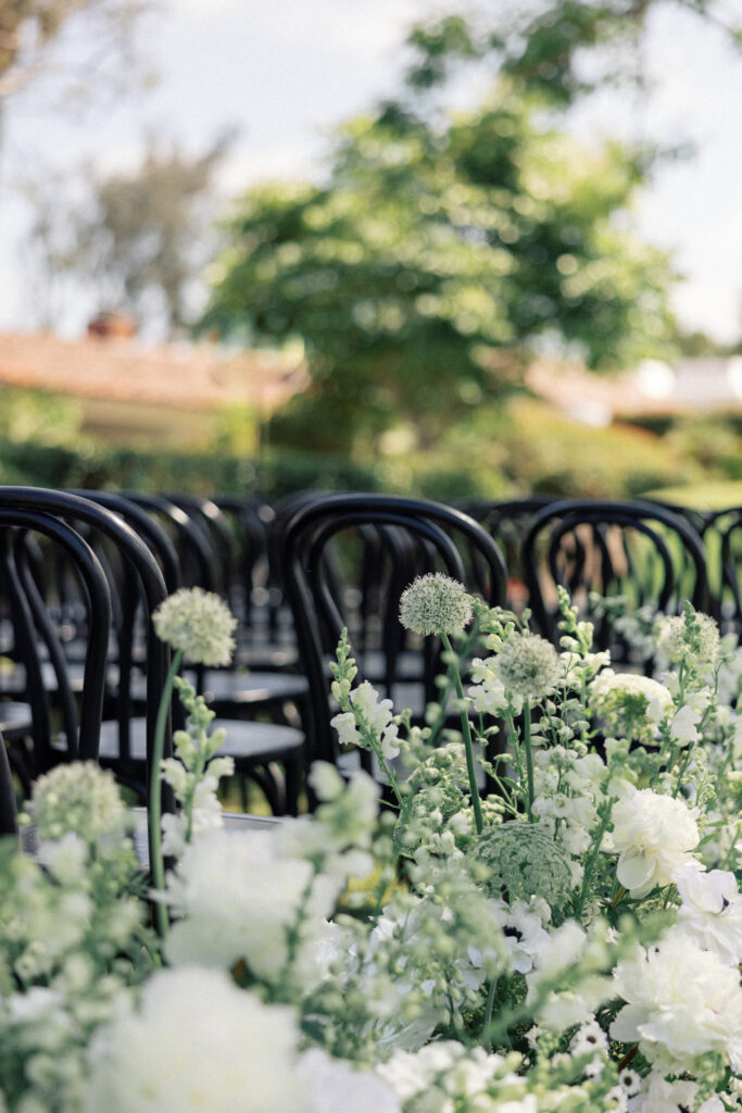 Photograph of white flowers with black chairs at a wedding ceremony by Kay Cushman.