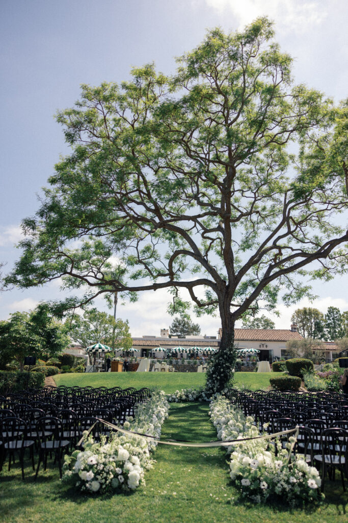 The wedding ceremony location at the Inn at Rancho Santa Fe, featuring a large tree covered in white flowers.
