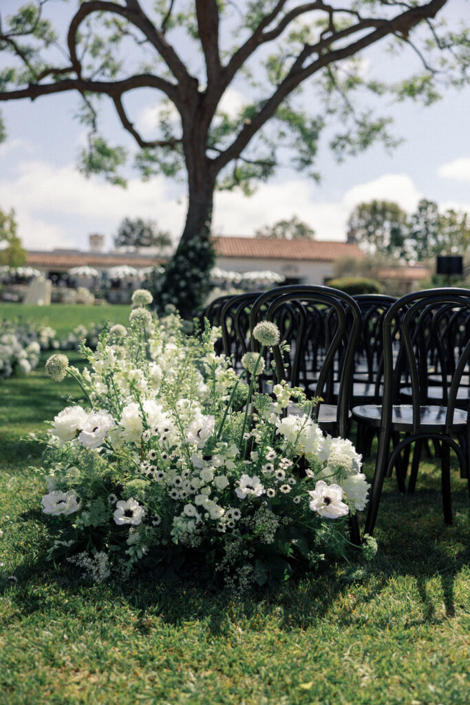 Photograph of white flowers with black chairs at a wedding ceremony by Kay Cushman at Rancho Santa Fe Inn.