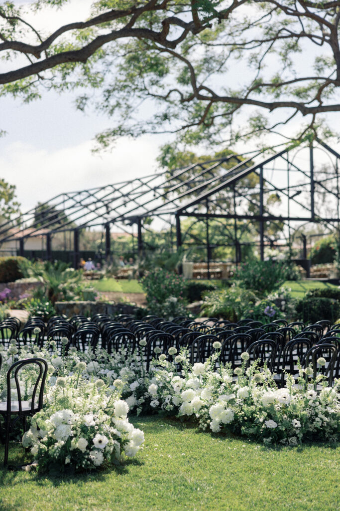 Photograph of white flowers with black chairs at a wedding ceremony by Kay Cushman in southern California.