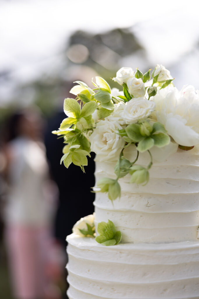 White and green wedding cake with hellebore flowers draped along the top.